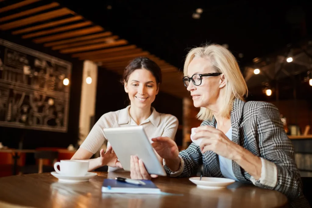Two restaurant managers reviewing revenue data on a tablet.